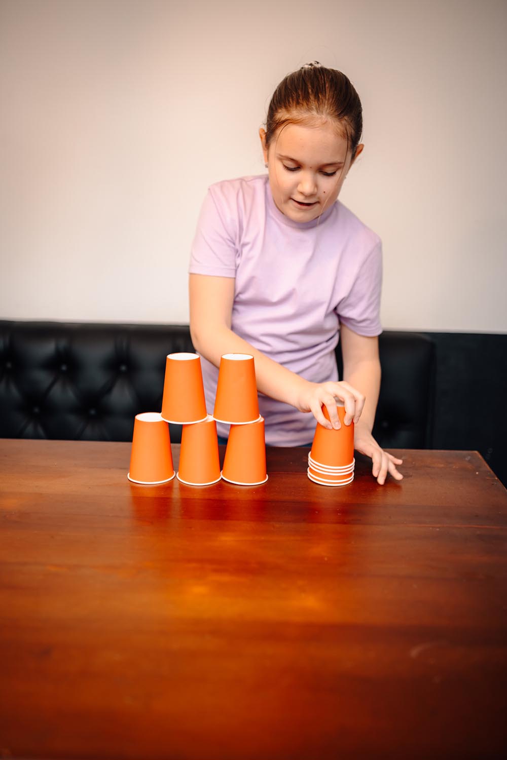 A child stacking orange paper cups into a tower